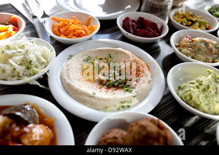 Una piastra di guarnito hummus sul tavolo circondato da vari tipi di insalate Foto Stock