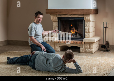 Padre e figlio rilassante accanto al fuoco Foto Stock