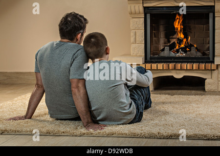 Padre e figlio rilassante accanto al fuoco Foto Stock