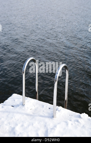 Una coperta di neve dock con una scala di andare in acque torbide Foto Stock
