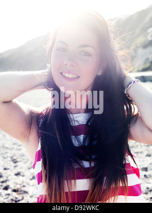 Una giovane donna sorridente allegramente mentre in spiaggia Foto Stock