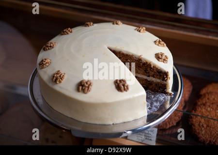 Una torta di carote su un display mobile in una gabbia con un pezzo mancante Foto Stock