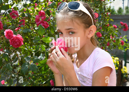 La ragazza odora di rose su un fiore-letto Foto Stock