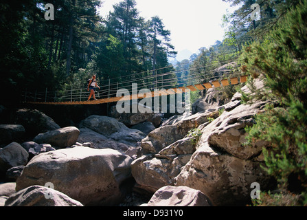 Una donna che cammina su un ponte di sospensione, Corse, Francia. Foto Stock