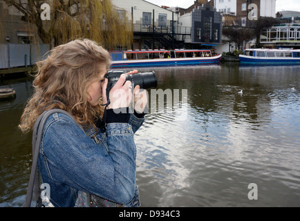 Una bella ragazza adolescente di prendere una fotografia al Camden Lock a Londra, Inghilterra, Regno Unito. Foto Stock