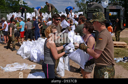 Sodiers della Bundeswehr e volontari compilare e caricare sacchi di sabbia per proteggere le aree da inondazione in Doemitz, Germania, 10 giugno 2013. I residenti della città la lotta contro l'acqua alta. Foto: Axel HEIMKEN Foto Stock