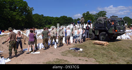 Sodiers della Bundeswehr e volontari compilare e caricare sacchi di sabbia per proteggere le aree da inondazione in Doemitz, Germania, 10 giugno 2013. I residenti della città la lotta contro l'acqua alta. Foto: Axel HEIMKEN Foto Stock