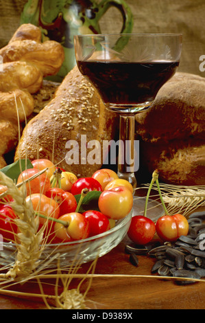 Natura morta con pane, cherrys, e vino sul tavolo di legno. Foto Stock