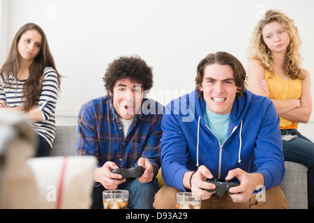 Gli uomini con i video giochi ignorando amiche Foto Stock