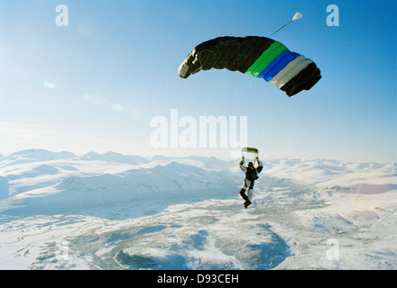 Un parachutist nell'aria oltre le montagne ricoperte di neve, Svezia. Foto Stock