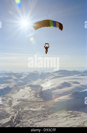 Un parachutist nell'aria oltre le montagne ricoperte di neve, Svezia. Foto Stock