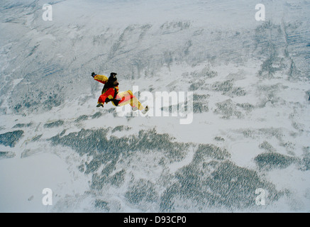 Un parachutist nell'aria oltre le montagne ricoperte di neve, Svezia. Foto Stock