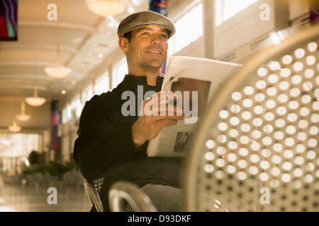 Uomo caucasico leggendo il giornale in cafe Foto Stock