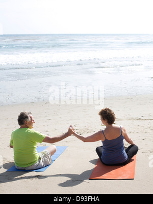 Coppia caucasica la pratica dello yoga sulla spiaggia Foto Stock