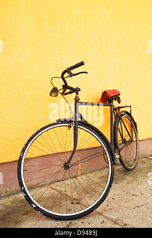 Vecchio vintage bicicletta nero appoggiato sulla parete. Foto Stock