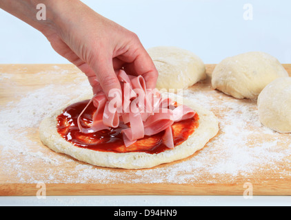 Cuocere topping pizza con fette di prosciutto Foto Stock