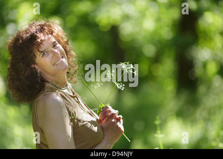 Persone di mezza età donna matura per godersi la natura holding di fiori selvaggi nella foresta Foto Stock