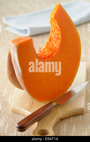 Close-up del cuneo di zucca sul tagliere con coltello su sfondo beige, Studio Shot Foto Stock