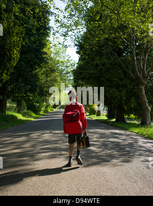 Un giovane ragazzo passeggiate a scuola Foto Stock