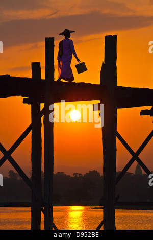 Il birmano utilizzare il teak U BEINS ponte per commutare tra il Lago Taungthaman presso sunrise - AMARAPURA, MYANMAR Foto Stock