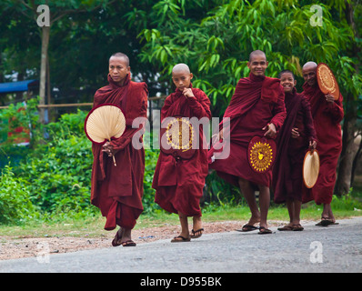 I monaci buddisti con ventole a piedi lungo la strada - BAGO, MYANMAR Foto Stock