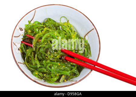 Vista dall'alto di insalata di alghe marine in vaso di ceramica con bacchette rosso isolato su sfondo bianco Foto Stock