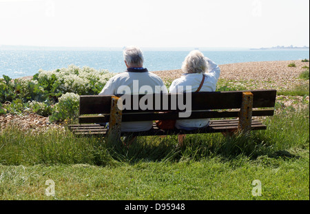 Coppia senior sul banco di lavoro che guarda al mare, Il Solent a Hayling Island Foto Stock