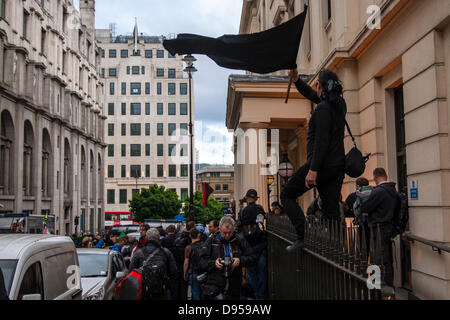 Londra, Regno Unito. 11 Giugno, 2013. Un anarchico onde la sua bandiera mentre in piedi in cima le ringhiere fuori Charing Cross a una stazione di polizia dove diversi manifestanti sono stati arrestati durante le manifestazioni contro il vertice del G8. Credito: Paolo Davey/Alamy Live News Foto Stock