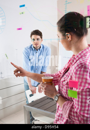 Il giovane e la giovane donna che lavora in un ufficio, guardando attraverso il vetro bordo, Germania Foto Stock