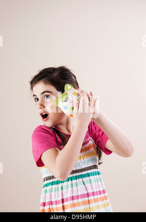 Ritratto di ragazza scuotendo salvadanaio e ascolto in Studio Foto Stock