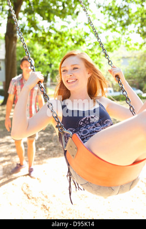 Coppia giovane trascorrere del tempo sulla swingset nel parco su una calda giornata estiva a Portland, Oregon, Stati Uniti d'America Foto Stock