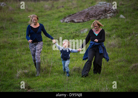 Gruppo di famiglia della madre, la figlia e la nipote correre giù per la collina per mano e ridendo Foto Stock