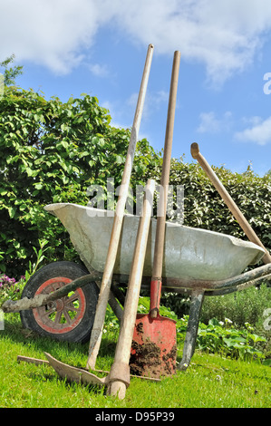 Vecchi attrezzi da giardinaggio e la carriola in giardino Foto Stock