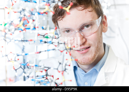 Germania, Ritratto di giovane scienziato con modello di DNA, sorridente Foto Stock
