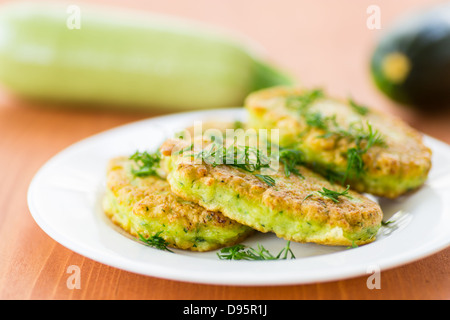 Zucchine fritte frittelle con aneto su una piastra Foto Stock