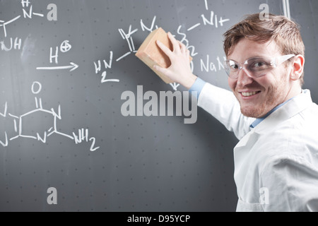 Germania, giovane scienziato cancellazione equazione chimica su chalk board Foto Stock