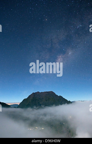 Visione notturna del Piton des Neiges Peak (3071m) prendendo al di sopra del cloud sull isola francese di la Reunion nell'Oceano Indiano. Foto Stock