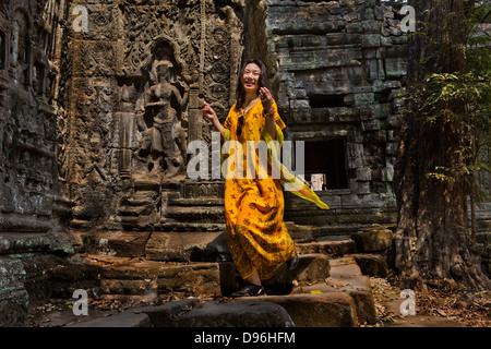 Donna cinese la modellazione di vestiti per una fotografia di moda in rovine di templi, Ta Prohm, Angkor tempio complesso. Ankor Wat Cambogia Foto Stock