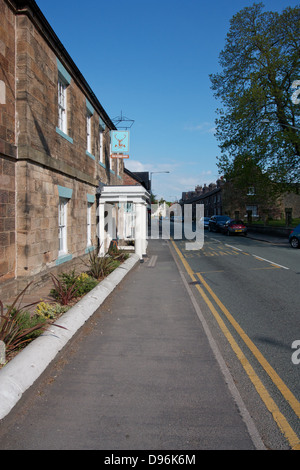 Strada principale attraverso il villaggio di Hawarden, Flintshire, il Galles del Nord con il Glynne Arms Hotel e casa pubblica sul lato sinistro Foto Stock