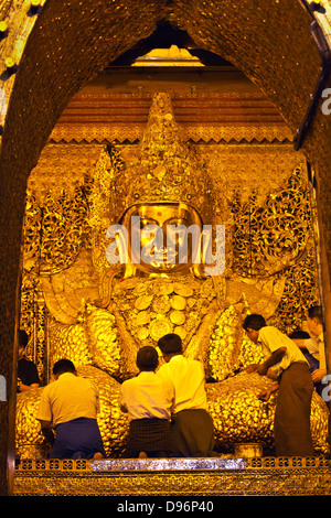 Gli uomini birmani indorare la tanto venerata MAHAMUNI BUDDHI all'interno della MAHAMUNI PAYA costruito da Re Bodwpaya nel 1784 - Mandalay, MYANMAR Foto Stock