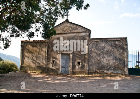 L'entrata frontale esterna di una vecchia chiesa cattolica sul bordo di una scogliera nel villaggio di piana, sulla costa occidentale della Corsica, Francia. Foto Stock