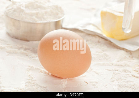 Un marrone uovo di pollo di fronte a forniture di cottura Foto Stock