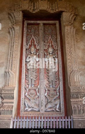 Chiudere verticale di legno intagliato porta all'entrata di Wat Ho Phra Keo o il Tempio del Buddha di Smeraldo di Vientiane Foto Stock