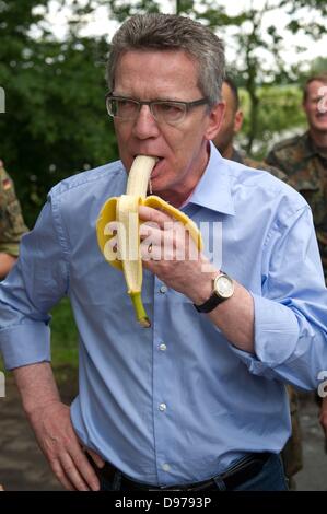 Penkefitz, Germania. Xiii Giugno, 2013. Ministro tedesco della difesa Thomas de Maiziere visite soldati della Bundeswehr ánd mangia una banana a una diga vicino Penkefitz, Germania, 13 giugno 2013. I soldati del battaglione della logistica 141 da Neustadt am Ruebenberge dighe rinforzato con sacchi di sabbia nella zona Luechow-Dannenberg. Foto: Sebastian Kahnert/dpa/Alamy Live News Foto Stock