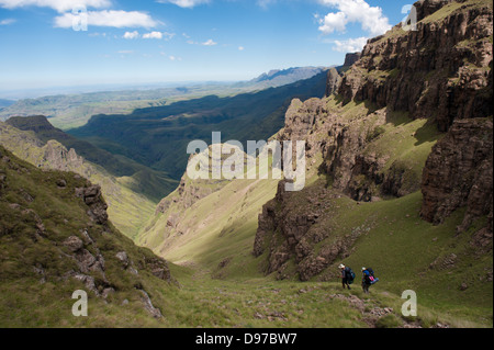 Gli escursionisti decending dalla scarpata a due gemelli Grotta, Ukhahlamba Drakensberg Park, Sud Africa Foto Stock