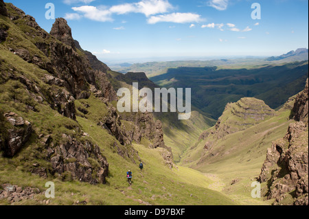 Gli escursionisti decending dalla scarpata a due gemelli Grotta, Ukhahlamba Drakensberg Park, Sud Africa Foto Stock