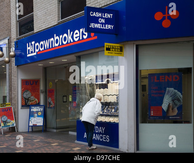 Donna che guarda nella finestra del negozio pawnbrokers Swindon, Wiltshire, Inghilterra, Regno Unito Foto Stock