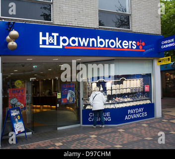 Donna che guarda nella finestra del negozio pawnbrokers Swindon, Wiltshire, Inghilterra, Regno Unito Foto Stock