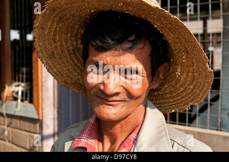 Uomo che indossa un cappello di paglia sorridente con la videocamera in un mercato in Myanmar (Birmania) Foto Stock