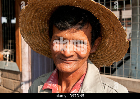 Uomo che indossa un cappello di paglia sorridente con la videocamera in un mercato in Myanmar (Birmania) Foto Stock